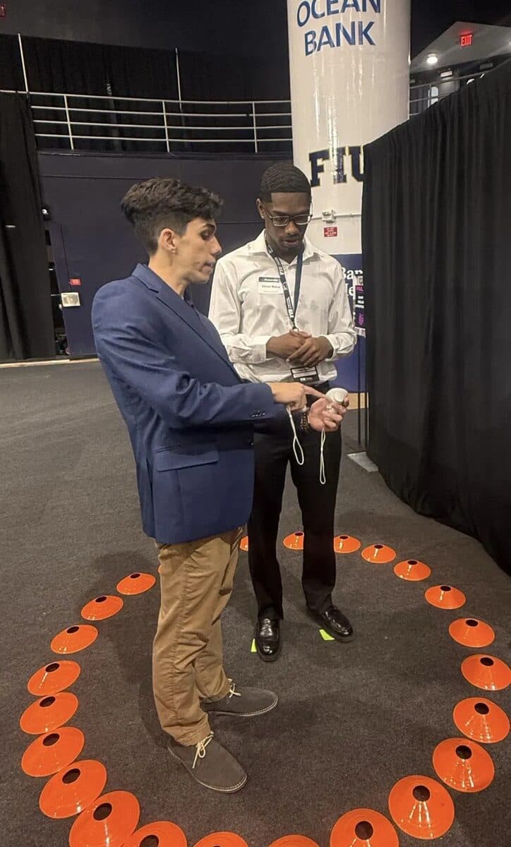 Tony showing a VR controller to a visitor at the FIU senior design showcase